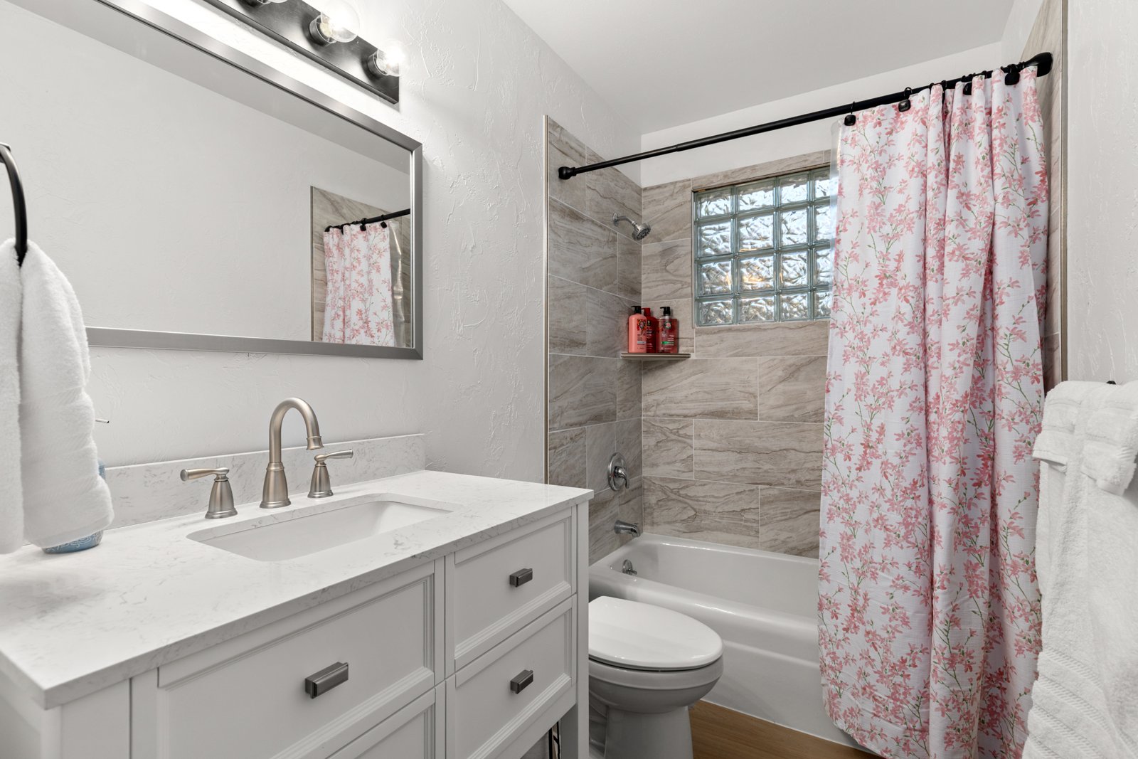 Remodeled bathroom with tiled tub surround and new vanity